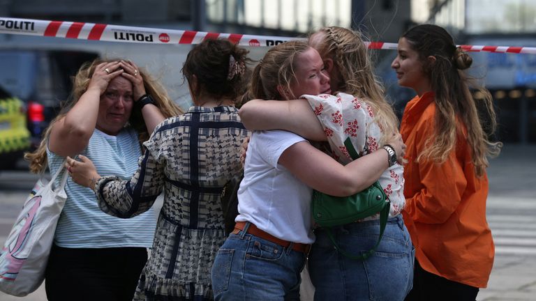 People hug each other outside the Fields shopping mall, after Danish police said they received reports of a shooting at the site, in Copenhagen, Denmark, July 3, 2022. Ritzau Scanpix / Olafur Steinar Gestsson via REUTERS ATTENTION EDITORS - THIS IMAGE IS SUPPLIED BY THIRD PARTY .  OUTSIDE DENMARK.  NO COMMERCIAL SALES OR EDITING IN DENMARK.