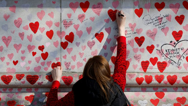 A person writes a message on The National Covid Memorial Wall, on national day of reflection to mark the two year anniversary of the United Kingdom going into national lockdown, in London, Britain, March 23, 2022. REUTERS/Peter Cziborra

