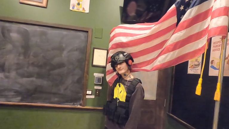 Robert Crimo poses in tactical gear in front of an American flag in one of his music videos