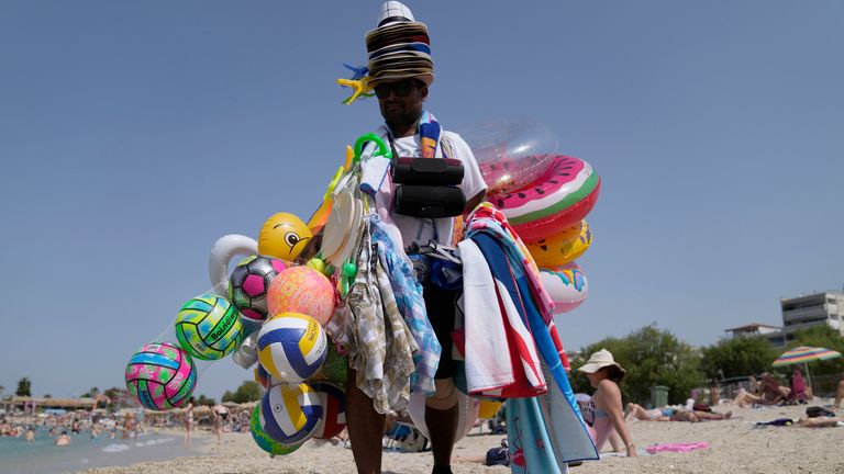 Um vendedor de Bangladesh vende acessórios marinhos na praia pública de Alimos, no sul de Atenas, Grécia, na quinta-feira, 23 de junho de 2022.  As temperaturas atingiram 40..C (104..F) em partes do sul da Grécia na sexta-feira, com as áreas da Europa central varridas pelas ondas de calor de junho.  Altas temperaturas e condições de seca em partes do continente aumentaram as preocupações com o risco de incêndios florestais.  (Foto AP/Thanasis Stavrakis)