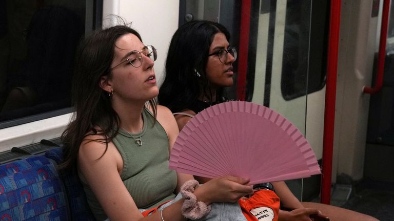 A woman holds a fan as she travels on the London Underground during a heatwave in London, Britain, July 17, 2022. REUTERS/Maja Smiejkowska