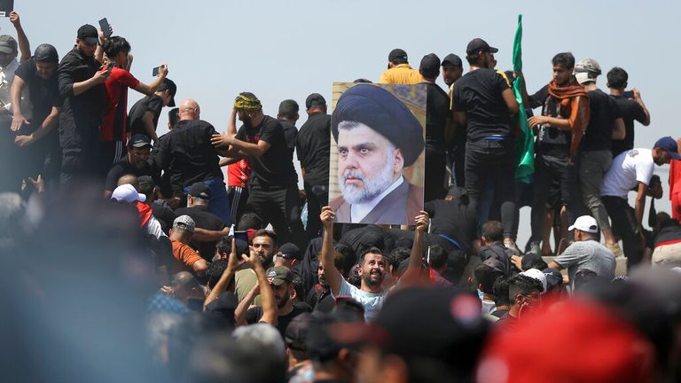 A protester holds a poster depicting Muqtada al-Sadr on a bridge leading towards the Green Zone area Pic: AP 