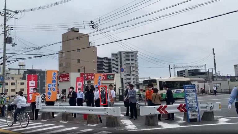 This image appears to show the suspect in the background as Mr Abe arrived for his speech