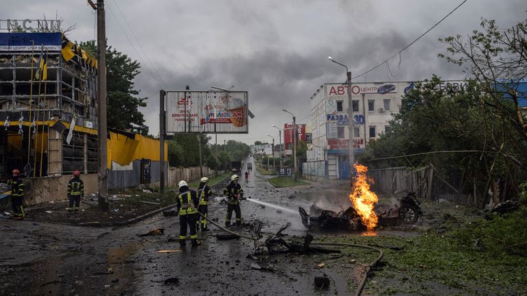 Rescue workers put out a car fire following a Russian attack in Kharkiv, Ukraine. Pic: AP
