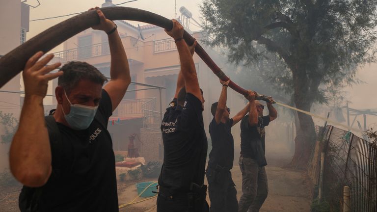 A police officer tries to extinguish a wildfire burning in the village of Vatera, on the island of Lesbos, Greece July 23, 2022. REUTERS / Alexandros Avramidis