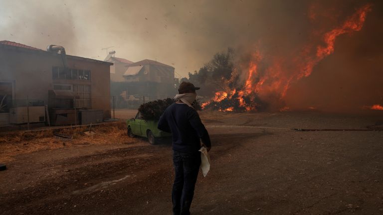 A police officer tries to extinguish wildfire burning in the village of Vatera, on the island of Lesbos, Greece July 23, 2022. REUTERS/Alexandros Avramidis