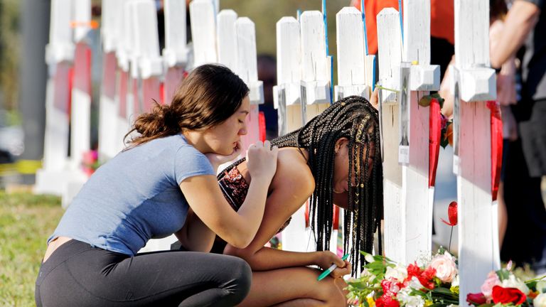 A senior at Marjory Stoneman Douglas High School weeps in front of a cross and Star of David for shooting victim Meadow Pollack while a fellow classmate consoles her at a memorial by the school in Parkland, Florida, U.S. February 18, 2018. REUTERS/Jonathan Drake