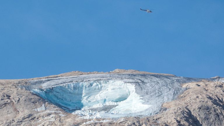 İtalyan Alpleri'ndeki Marmolada buzulunun üzerinde bir arama helikopteri görülüyor.