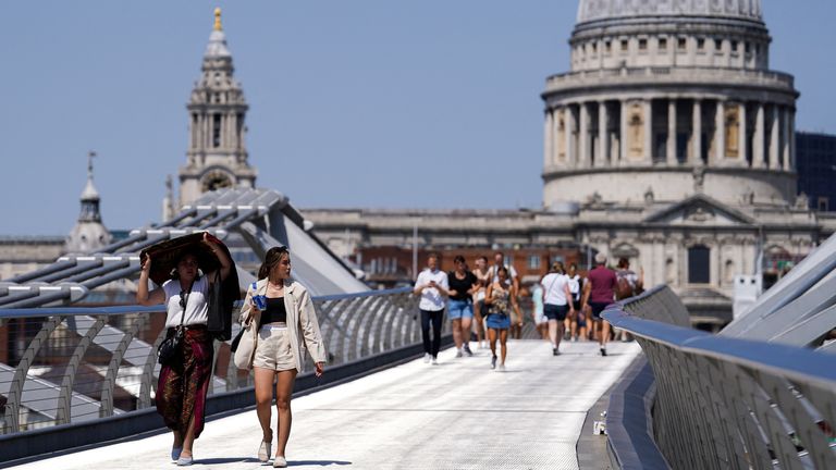 People cover themselves from the sun at Millennium Bridge during a heatwave, in London, Britain, July 18, 2022. REUTERS/Maja Smialkowska
