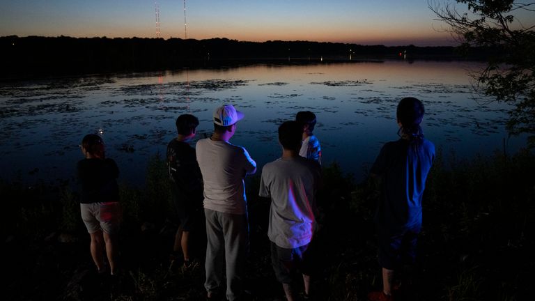 Friends and family gather at Lake Vadnais after news of a dead child was pulled from the lake, Friday, July 1, 2022 in Vadnais Heights, Minn.  The bodies of two children have been recovered from Lake Minnesota, and searchers are still searching for a third they fear may have been intentionally drowned.  (Alex Kormann / Star Tribune via AP)