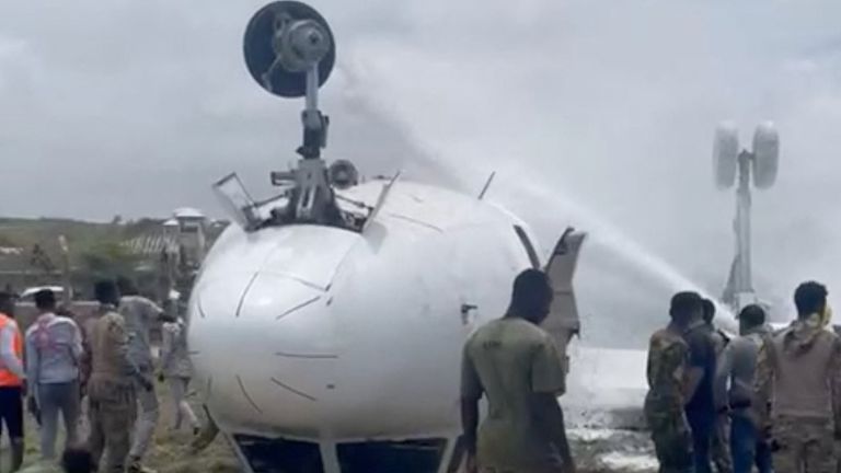 18 Temmuz 2022'de Mogadişu'da acil iniş yaptıktan sonra ters dönen uçağa itfaiye ekipleri su püskürtüyor. 