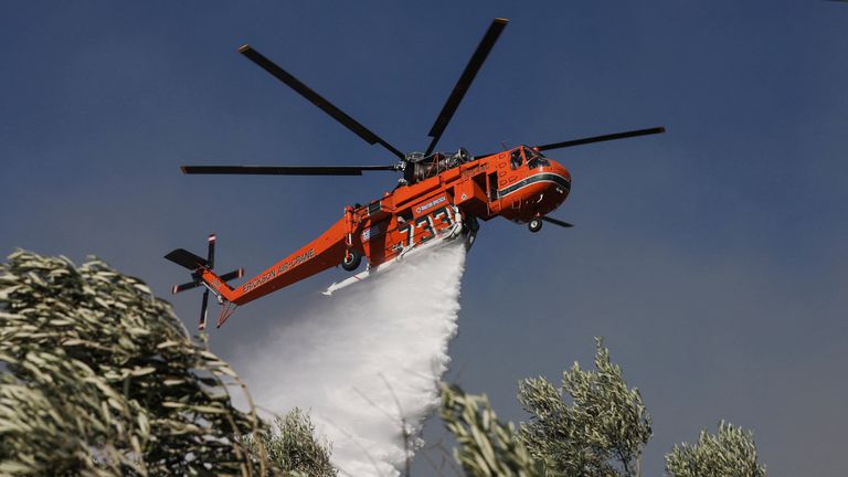 A firefighting helicopter makes a water drop as a wildfire burns in the Pikermi suburb of Athens, Greece, July 20, 2022. REUTERS/Louiza Vradi
