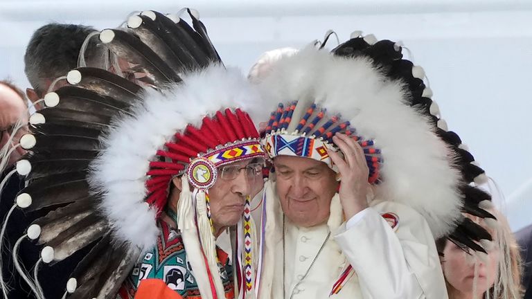 Pope Francis puts on an indigenous headdress during a meeting with indigenous communities, including First Nations, Metis and Inuit, at Our Lady of Seven Sorrows Catholic Church in Maskwacis, near Edmonton, Canada, Monday, July 25, 2022. Pope Francis begins a "penitential" visit to Canada to beg forgiveness from survivors of the country&#39;s residential schools, where Catholic missionaries contributed to the "cultural genocide" of generations of Indigenous children by trying to stamp out their languages, cultures and traditions. Francis set to visit the cemetery at the former residential school in Maskwacis. (AP Photo/Gregorio Borgia)