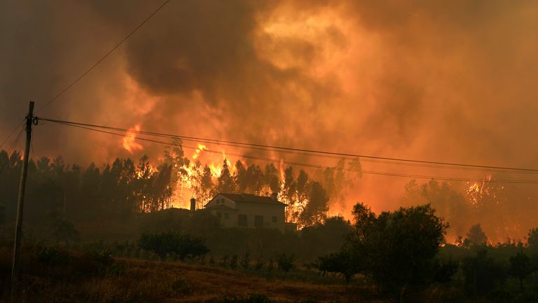A forest fire closes on a house in the village of Bemposta, near Ansiao, central Portugal, Wednesday, July 13, 2022. Thousands of firefighters in Portugal continue to battle fires all over the country that forced the evacuation of dozens of people from their homes. (AP Photo/Armando Franca)