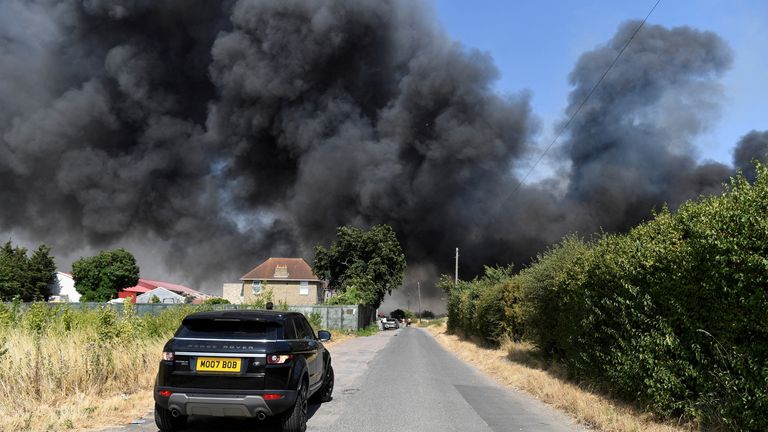 A car drives near a fire that burns during a heatwave, in Rainham, east London, Britain, July 19, 2022. REUTERS/Tony O&#39;Brien
