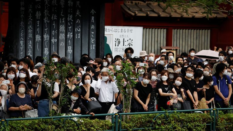 People wait for end of the funeral of the late former Japanese Prime Minister Shinzo Abe, who was shot while campaigning for a parliamentary election, outside the Zojoji temple in Tokyo, Japan July 12, 2022. REUTERS/Issei Kato
