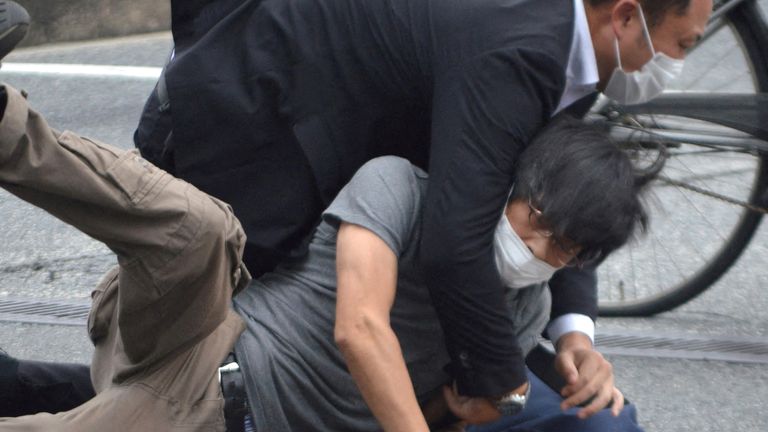 Seorang pria yang diyakini sebagai tersangka ditahan oleh polisi.  Foto: Yomiuri Shimbun via Reuters