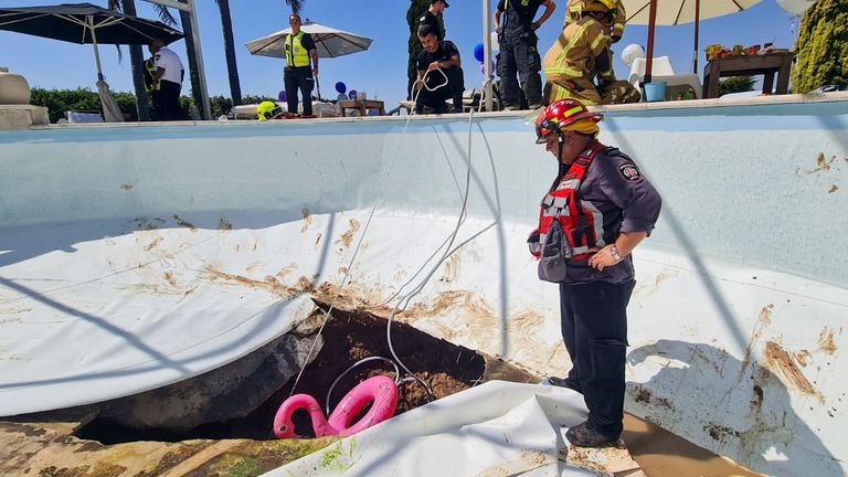 In this photo provided by Israel Fire and Rescue Services, Israeli firemen and rescuers work in a sinkhole formed in a swimming pool in Karmi Yosef, Israel, Thursday, July 21, 2022. Israeli police say they placed a couple under house arrest, a day after a man attending a party at their villa died after being sucked into a sinkhole that formed at the bottom of their swimming pool. The incident happened during a private party the couple hosted at their house in the town of Karmi Yosef, 40 kilometers (25 miles) southeast of Tel Aviv. (Israeli Fire and Rescue Services via AP)