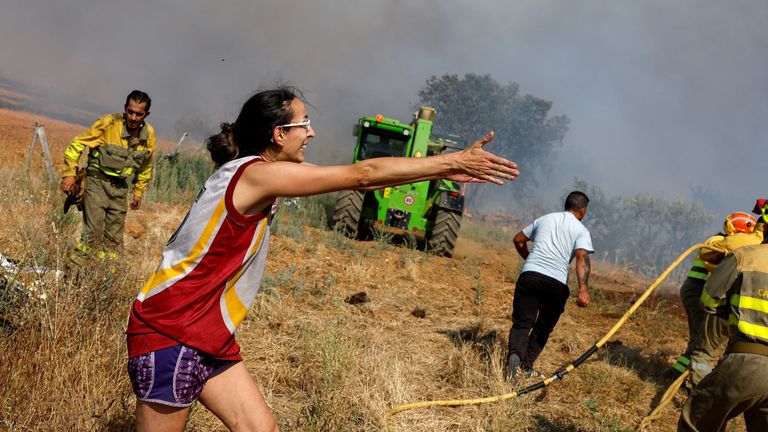 A woman gestures as firefighters work at the site of a wildfire amid Spain&#39;s second heatwave of the year, in Faramontanos de Tabara, Spain, July 19, 2022. REUTERS/Borja Suarez
