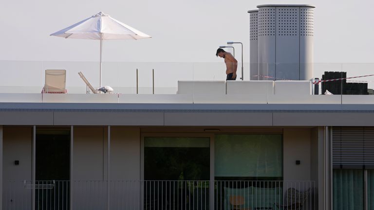 A man in swimming shorts showers on the roof of an apartment complex in Madrid, Spain, Tuesday, July 12, 2022. A new heat wave in Spain and Portugal is expected to hit lasts until the weekend.  High temperatures have been steadily escalating, raising fears of more uncontrolled wildfires.  (AP Photo / Paul White)