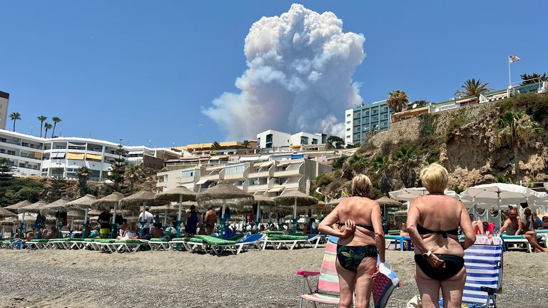 İnsanlar, 15 Temmuz 2022'de İspanya'nın Torremolinos kentindeki Playa del Bajondillo plajından görülen, Malaga'daki bir orman yangınının neden olduğu duman bulutlarına bakıyor. REUTERS/Hannah McKay