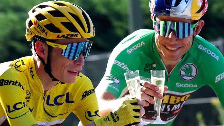 Denmark's Jonas Vingegaard, wearing the yellow jersey of the overall top team, toasts a glass of champagne with his Belgian teammates, Wout Van Aert, wearing the blue jersey of the best sprinter in stage 21 of the Tournament The Tour de France is over 116 kilometers (72 miles) long with a start at Paris la Defense Arena and a finish on the Champs Elysees in Paris, France, Sunday, July 24, 2022. (Thomas Samson / Pool Photo via AP)