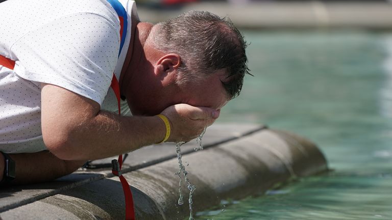 A person wets their face in a fountain at Trafalgar Square in central London. Picture date: Tuesday July 19, 2022.
