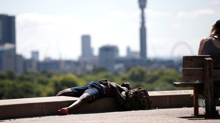 A man lies in the sun at Primrose Hill, in London, Britain, July 15, 2022. REUTERS/Peter Nicholls

