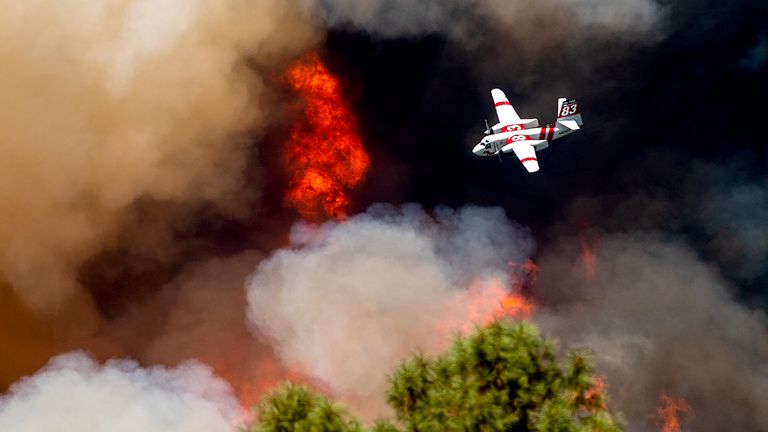 An air tanker flies past flames while battling the Oak Fire in Mariposa County, California Pic: AP 