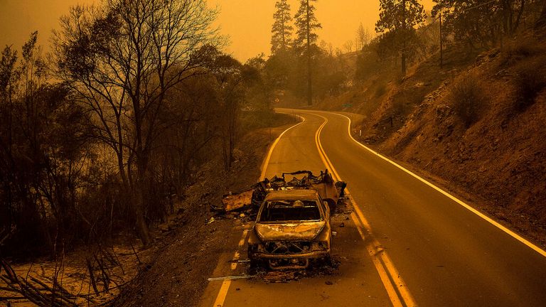 A scorched pickup truck rests on California Highway 96 in Klamath National Forest, Calif., as the McKinney Fire burns nearby, Saturday, July 30, 2022. (AP Photo/Noah Berger)