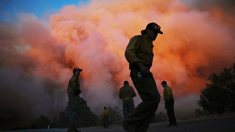 U.S. Forest firefighters stand along the Triangle as they watch a wildfire known as the Oak Fire burn east of the Midpines in Mariposa County, California, Friday, July 22, 2022. Fast-moving near Yosemite National Park that broke out Friday afternoon and prompted firefighters to evacuate has made progress from an earlier blaze that burned to the edge of a giant grove of Sequoias.  (Eric Paul Zamora / Ong Fresno via AP)