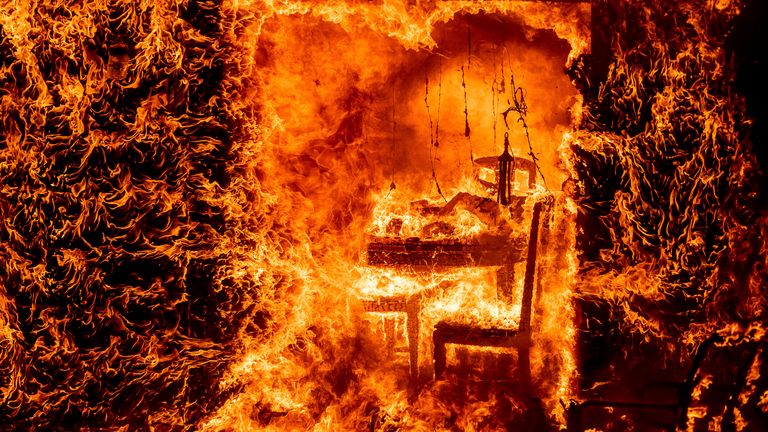 Le fiamme avvolgono una sedia all'interno di una casa in fiamme mentre un fuoco di quercia brucia nella contea di Mariposa, in California, sabato 23 luglio 2022 (Foto AP/Noah Berger)