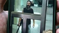 11 August 2022, Lebanon, Beirut: A man holding a smartphone shows a screen grab taken from a video of an armed depositor gesturing at employees of a local Bank in Beirut after he stormed the branch and held employees and customers as hostages. The man, who entered the bank carrying a machine gun and gasoline, demanded to be handed over part of his deposited money, which amounts to USD&#39;209,000. 