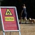 A person walks near a fire warning sign following a long period of hot weather and little rainfall, in Richmond Park, in London, Britain August 4, 2022. REUTERS/Toby Melville