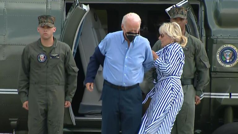 President Joe Biden, struggles to put his jacket on after exiting a helicopter. After finally getting his arm into the jacket he drops his glasses onto the tarmac.