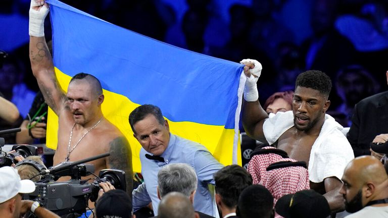 Ukraine&#39;s Oleksandr Usyk, left, celebrates after beating Britain&#39;s Anthony Joshua, as they both hold a Ukrainian flag after their world heavyweight title fight at King Abdullah Sports City in Jeddah, Saudi Arabia, Sunday, Aug. 21, 2022. (AP Photo/Hassan Ammar)