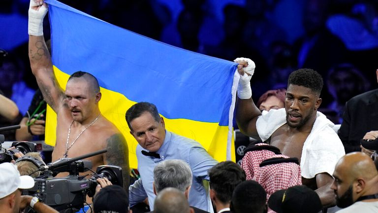 Oleksandr Usyk of Ukraine, left, celebrates after defeating England's Anthony Joshua, as they both hold the Ukrainian flag after their world heavyweight title match at King Abdullah Sports City in Jeddah, Saudi Arabia, Sunday, Aug. August 21, 2022. (AP Photo / Hassan Ammar)