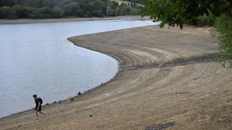 A man walks along the shoreline as reduced water levels are seen at Ardingly Reservoir, ahead of regional restrictions over water usage being implemented in the hot and dry weather, Ardingly, southern Britain, August 4, 2022. REUTERS/Toby Melville

