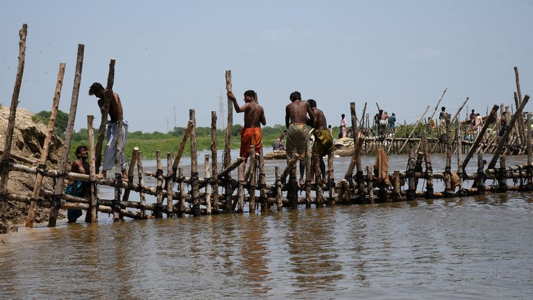People prepare a barrier with wooden logs and sand bags to stop flood waters, following rains and floods during the monsoon season in Puran Dhoro, Badin, Pakistan August 30, 2022. REUTERS/Yasir Rajput NO RESALES. NO ARCHIVES.
