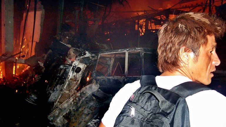 An unidentified man is seen walking past wreckage after the bombs detonated