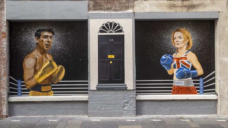 People walking past a mural on Hill Street in Belfast by Ciaran Gallagher Art, commissioned by local bar owner Willie Jack, showing conservative party candidates, Rishi Sunak and Liz Truss as two boxers about to fight it out to be the UK Prime Minister. Picture date: Tuesday August 16, 2022.
