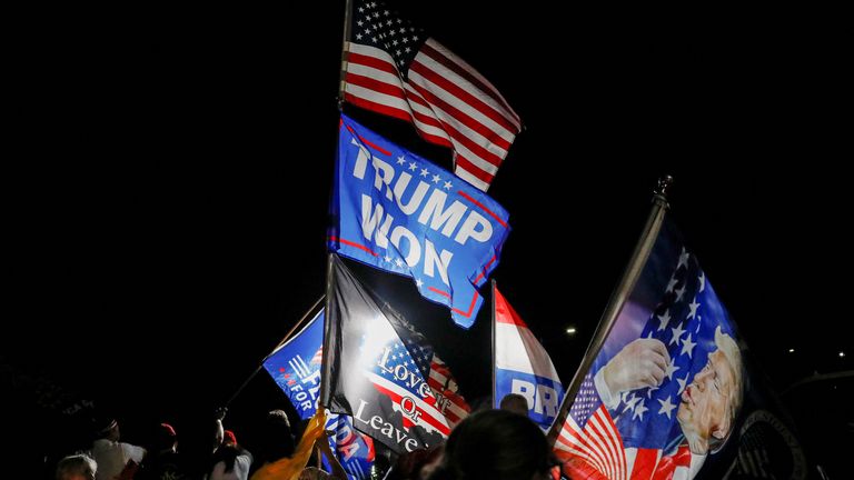 Supporters of former U.S. President Donald Trump wave flags as they gather outside his Mar-a-Lago home after Trump said that FBI agents raided it, in Palm Beach, Florida, U.S., August 8, 2022. REUTERS/Marco Bello
