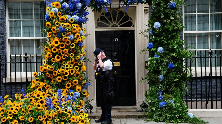 A police officer stands by an arch of sunflowers at the door of 10 Downing Street, London, to show the UK's support for Ukraine, who celebrate their independence day on Wednesday.  Date taken: Tuesday, August 23, 2022.