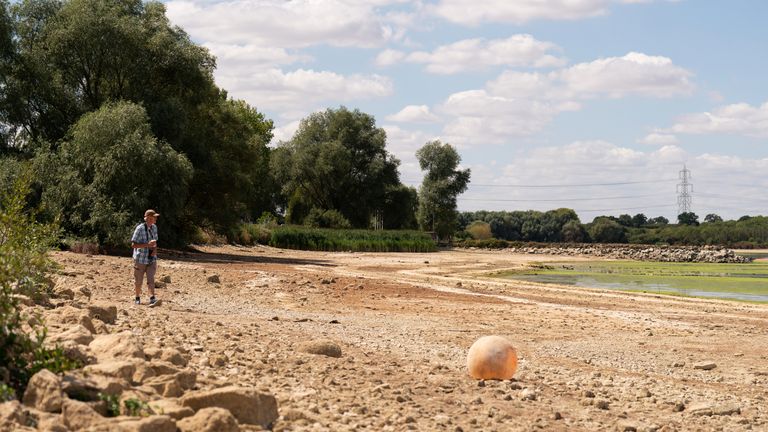 A man stands in the basin of Grafham Water near Huntingdon in Cambridgeshire, where water is receding during the drought. Britain is braced for another heatwave that will last longer than July&#39;s record-breaking hot spell, with highs of up to 35C expected next week. Picture date: Monday August 8,