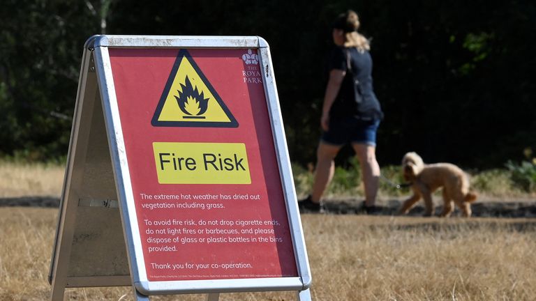 A person walks near a fire warning sign following a long period of hot weather and little rainfall, in Richmond Park, in London, Britain August 4, 2022. REUTERS/Toby Melville