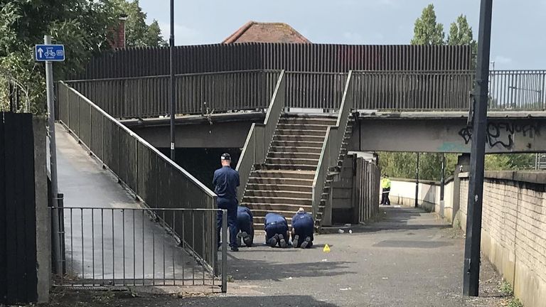 Police inspect the ground on the footpath between Balnacraig Avenue and Ballogie Avenue following a shooting on Monday in Dog Lane in Brent, north-west London, where a man is in a serious condition in hospital and two other people were injured. Picture date: Tuesday August 16, 2022.

