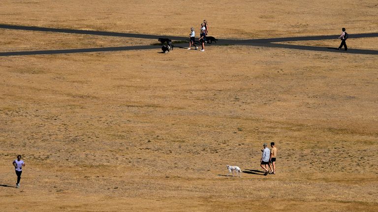 People walk through dry and sun burnt grass in Greenwich Park in London, Tuesday, Aug. 9, 2022. Britain is braced for another heatwave that will last longer than July&#39;s record-breaking hot spell, with highs of up to 35 C expected next week. (AP Photo/Frank Augstein)