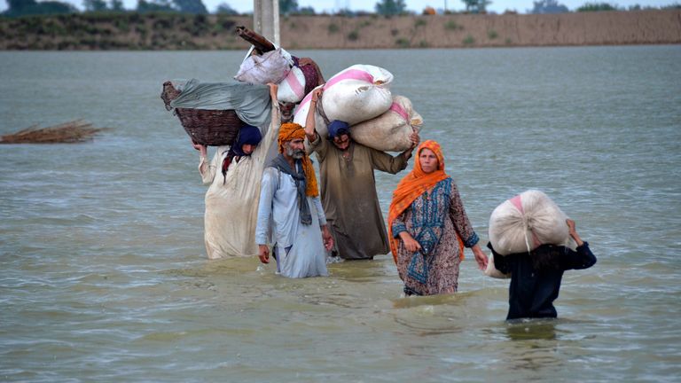 A displaced family wades through a flooded area after heavy rainfall, in Jaffarabad, a district of Pakistan&#39;s southwestern Baluchistan province, Wednesday, Aug. 24, 2022. Rains have triggered flash floods and wreaked havoc across much of Pakistan since mid-June, leaving 903 dead and about 50,000 people homeless, the country&#39;s disaster agency said Wednesday. (AP Photo/Zahid Hussain)
