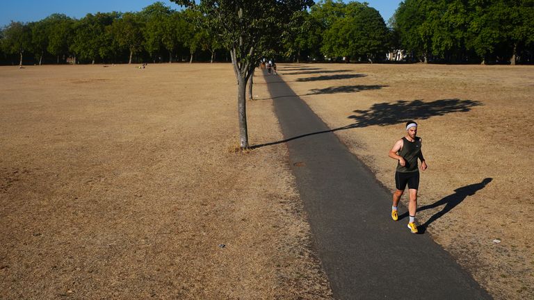A person jogging on a path amongst dead grass in Victoria Park, east London. The Met Office has issued an amber heat warning running between Thursday and Sunday, which could see temperatures peak at 36C across southern England and eastern Wales, with some areas facing an "exceptional" risk of wildfires as the Fire Severity Index is raised to its highest level. Picture date: Thursday August 11, 2022.

