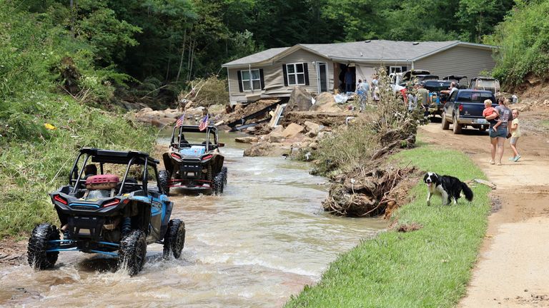 ATV drivers ferrying generator fuel and water drive around Jessica Willett&#39;s home, which was torn from its foundations during flooding and left in the middle of the road, along Bowling Creek, Kentucky, U.S. July 31, 2022. Chris Kenning/USA Today Network via REUTERS NO RESALES. NO ARCHIVES. MANDATORY CREDIT
